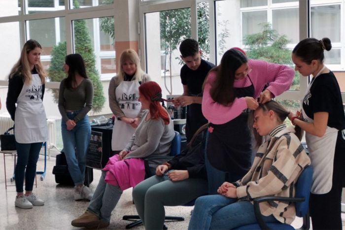 FOTO: Dobojski Info | DOBOJ: Učenici frizerskog smjera izrađuju pletenice povodom Dana škole